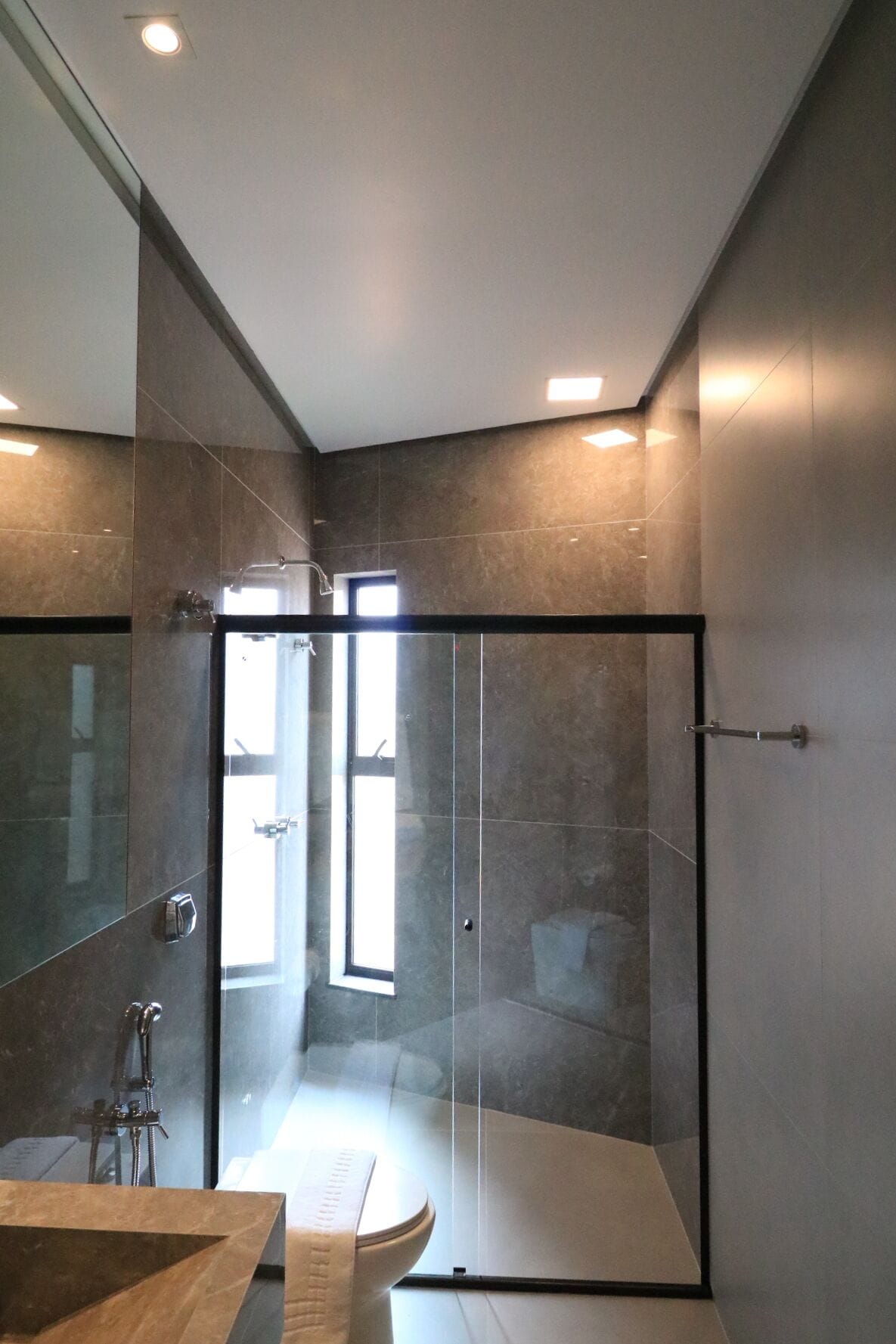A modern bathroom with a glass shower enclosure, a large mirror, and a wooden vanity.