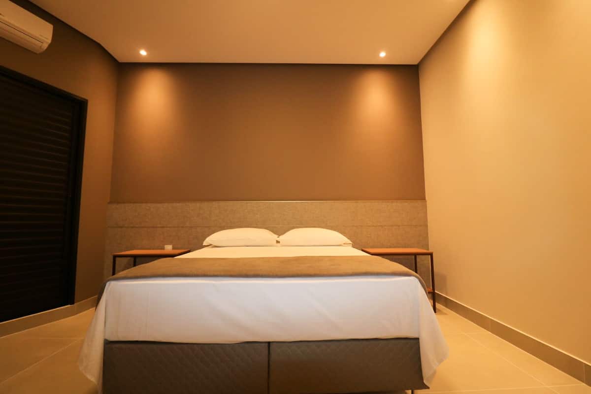 Ein Hotelzimmer mit einem Bett, zwei Nachttischen und einer Wandklimaanlage.