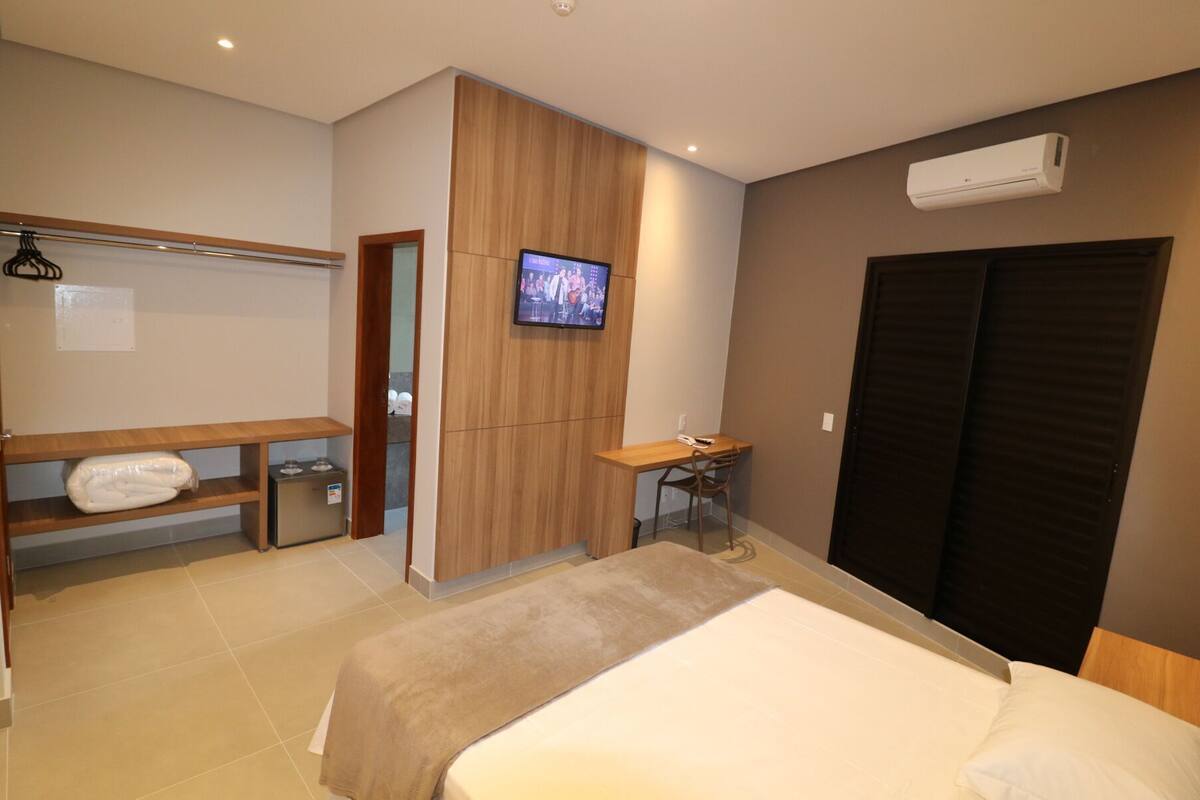 Ein Hotelzimmer mit Bett, Schreibtisch, Fernseher, Kleiderschrank und Bad.