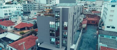 A modern hotel with a prominent sign, surrounded by residential buildings with red-tiled roofs.