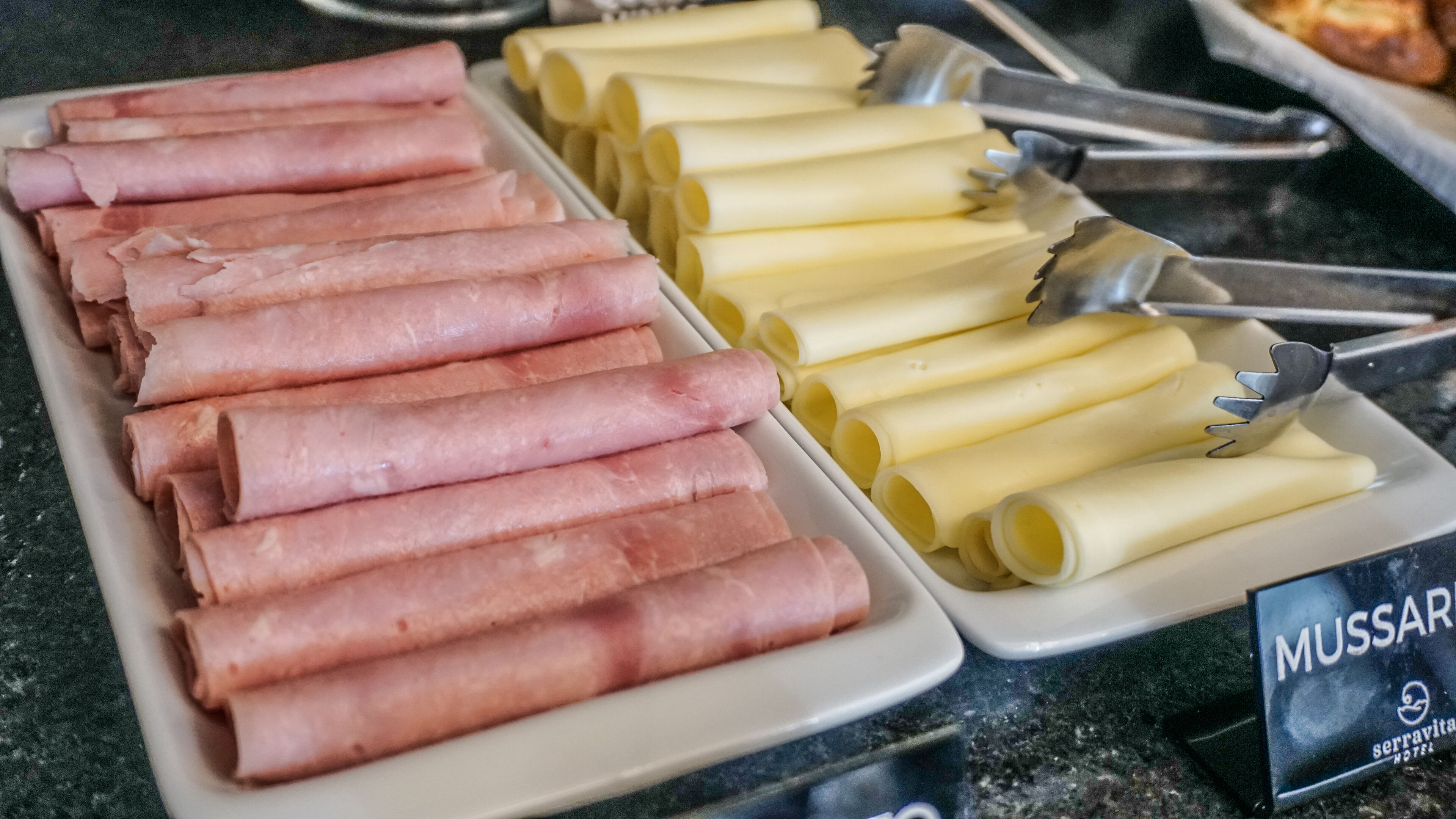 A buffet with sliced meats and cheese.