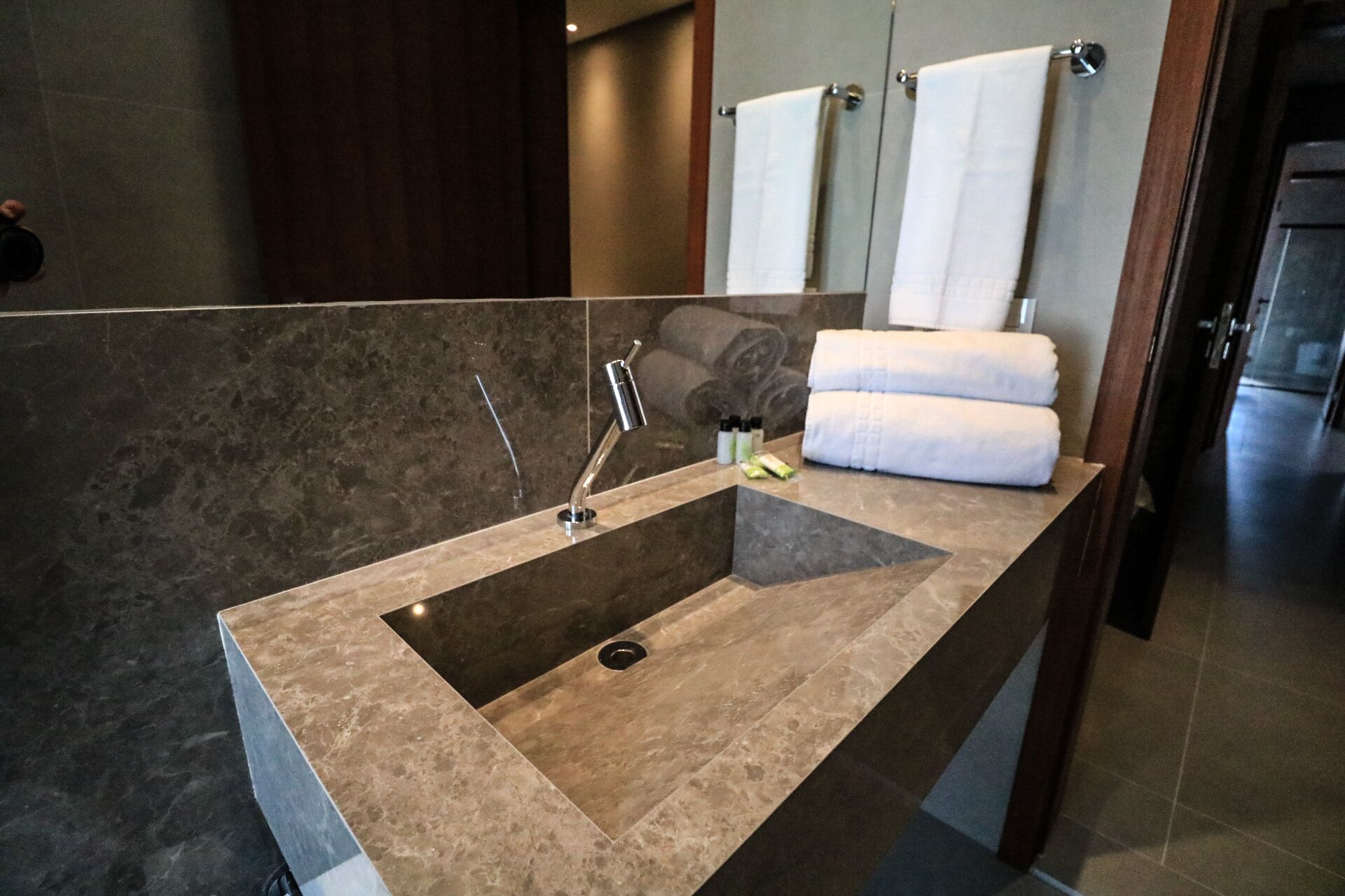 A modern bathroom with a rectangular sink, a mirror, and two towels hanging on a towel rack.