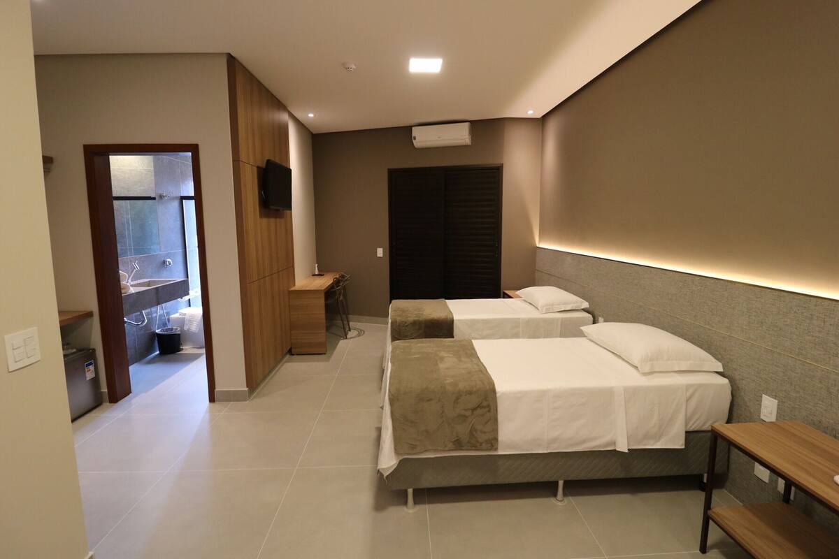 Ein Hotelzimmer mit zwei Betten, einem Schreibtisch, einem Fernseher und einem Badezimmer mit Dusche.