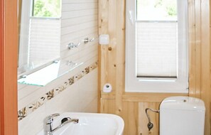 Ein Badezimmer mit einem weißen Waschbecken, einem Spiegel und einem Fenster.