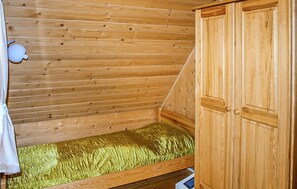 Eine Holzhütte mit Etagenbett, Holzschrank und einem kleinen weißen Gegenstand an der Wand.