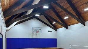 An indoor basketball court with wooden flooring, a basketball hoop, and a volleyball net. - Golf Villa - Pool Access + Private Deck (Galena)