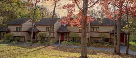 A row of three-story buildings with a uniform architectural style, surrounded by trees with autumn foliage.