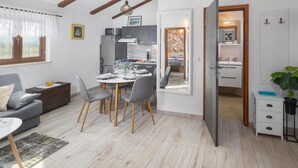 Ein modernes Wohnzimmer mit Essbereich, einer Küche und einem durch eine offene Tür einsehbaren Badezimmer.
