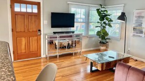 A living room with a wooden door, a TV on a stand, a glass coffee table, a plant, and a lamp. - RustlingLeaves.Kg&Qn.2ndFlrGarageLaundry (Los Angeles)