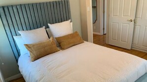 A neatly made bed with a grey headboard, white bedding, and two brown pillows. - RustlingLeaves.Kg&Qn.2ndFlrGarageLaundry (Los Angeles)