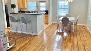 A modern kitchen with a central island, bar stools, and a dining area with a table and chairs. - RustlingLeaves.Kg&Qn.2ndFlrGarageLaundry (Los Angeles)