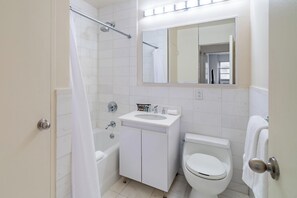 A bathroom with a bathtub, sink, toilet, and a mirror above the sink.