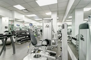 Una palestra con diverse attrezzature per esercizi, tra cui manubri, una panca per pesi e una macchina Cybex.