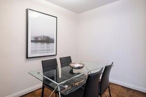 A dining area with a glass table, black chairs, and a framed picture on the wall.
