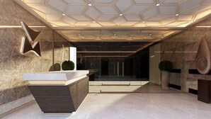 En moderne lobby med en reception, et geometrisk loftsdesign og en marmorgulv.