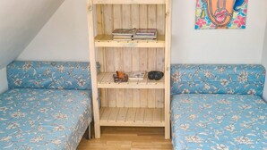 A room with a wooden bookshelf, two blue floral-patterned sofas, and a colorful painting on the wall. - Beautiful apartment in Wolin (Wolin)