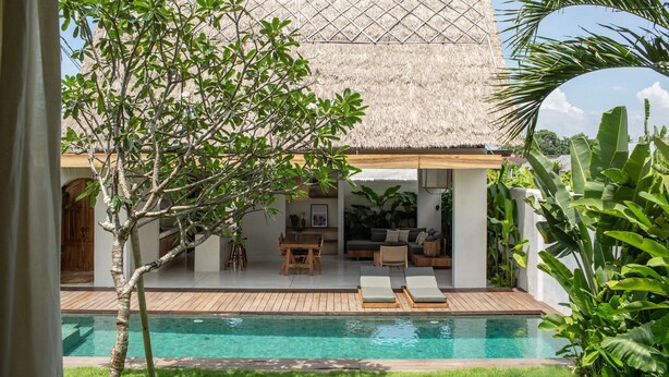 A poolside area with a thatched-roof structure, a wooden deck, and a seating area with a table and chairs. - Las Lunas Villas Canggu (Canggu)