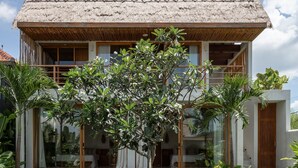 A modern house with a thatched roof, large windows, and a swimming pool in the foreground. - Las Lunas Villas Canggu (Canggu)