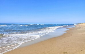 Une plage à l’eau d’un bleu limpide et au rivage sablonneux.