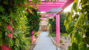 Un sendero que conduce a una estructura de madera con un arco rosa.