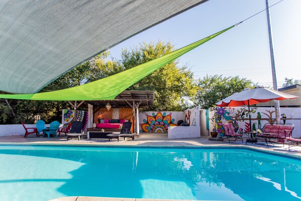 A swimming pool with lounge chairs and a shaded area.