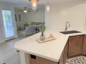 A modern kitchen with a white countertop, wooden cabinets, a built-in sink, pendant lighting, and a potted plant. - Mountain view Hideaway w/3 Pools (Scottsdale)