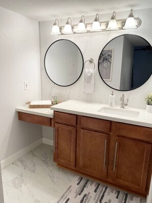 A bathroom with a white vanity, two round mirrors, a sink, and a towel rack. - Mountain view Hideaway w/3 Pools (Scottsdale)
