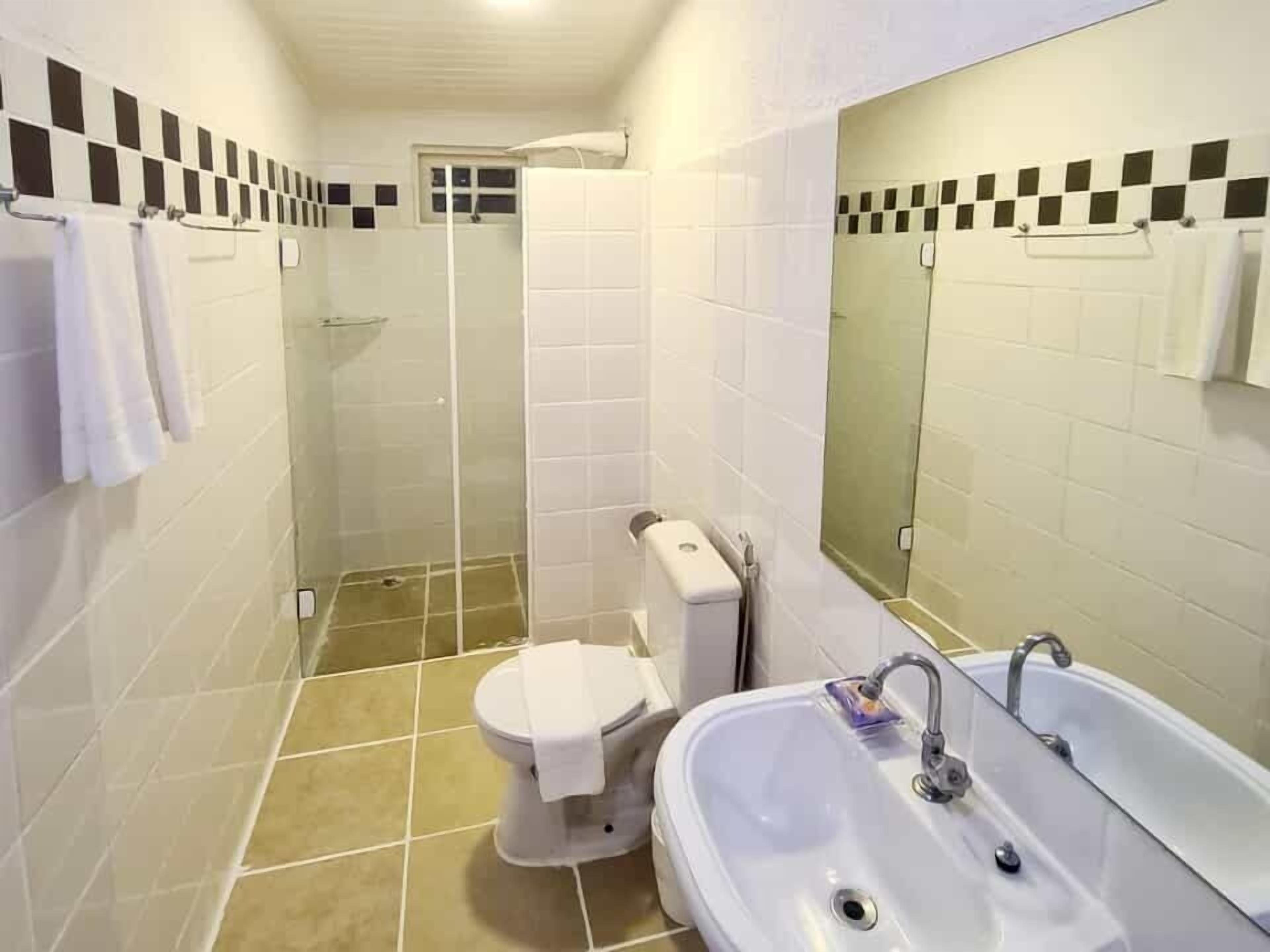 A bathroom with a toilet, shower, and sink.