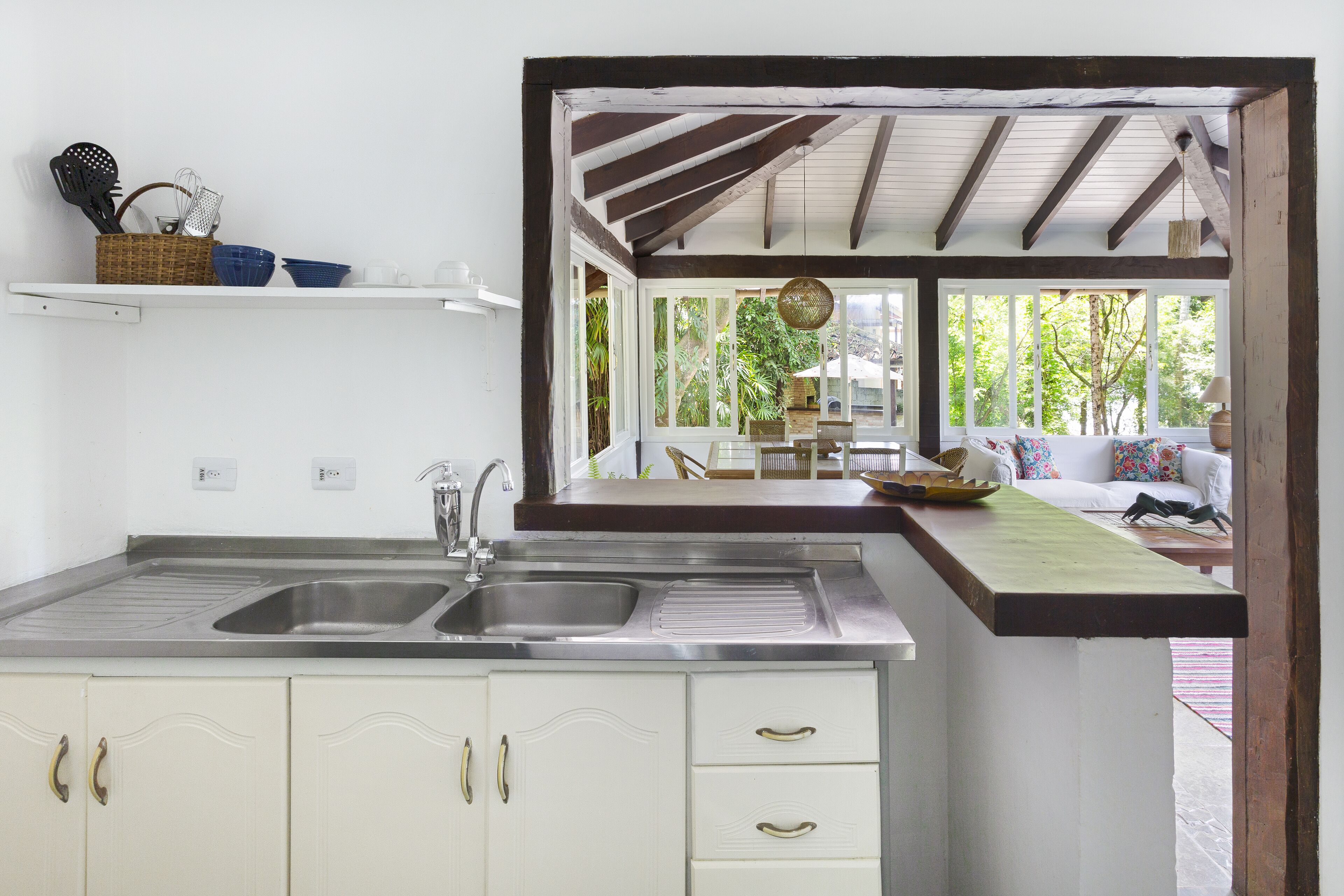 A kitchen with a double sink, white cabinets, and a wooden ceiling.