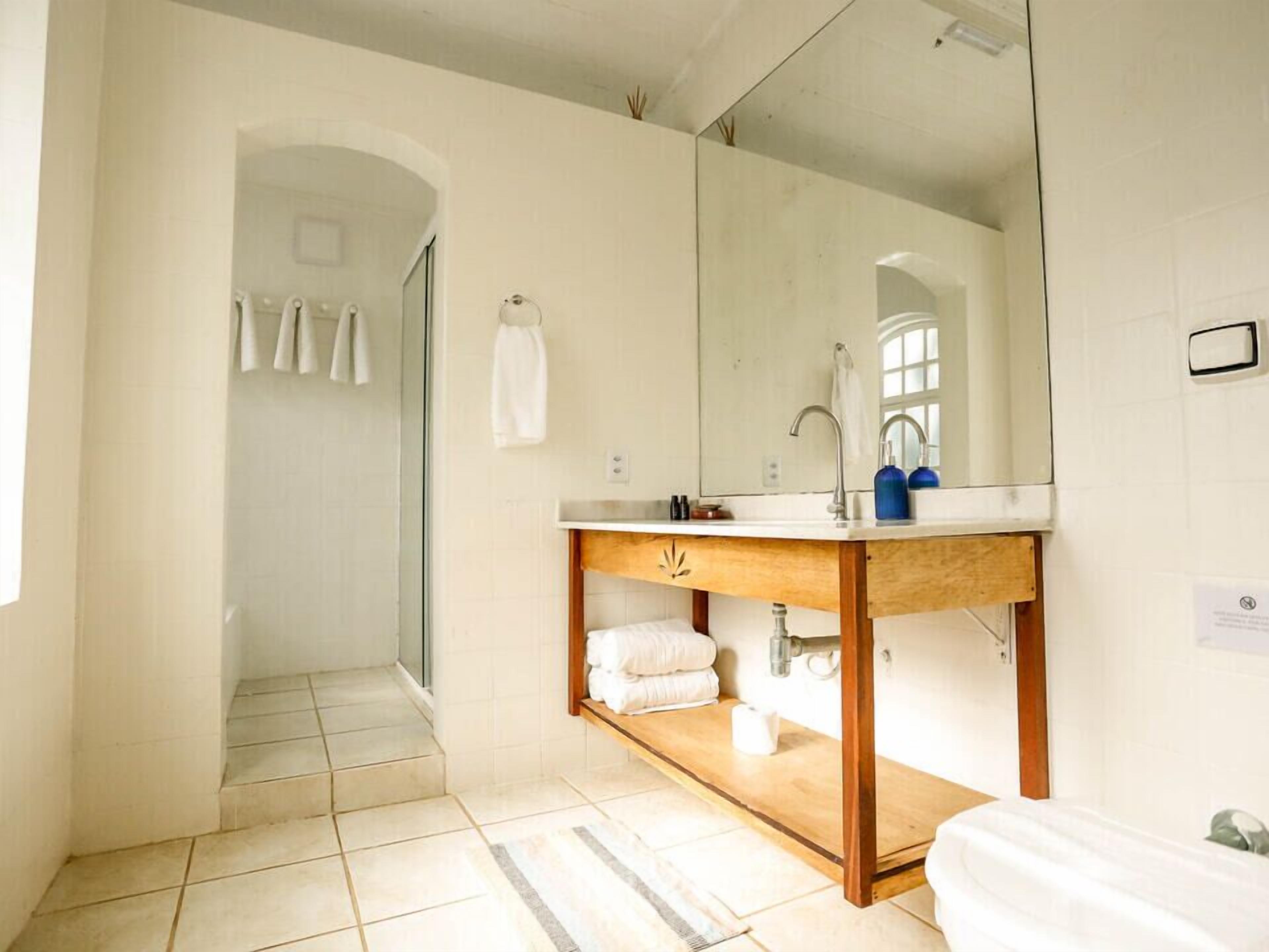 Un baño con tocador de madera, un espejo grande y una zona de ducha.
