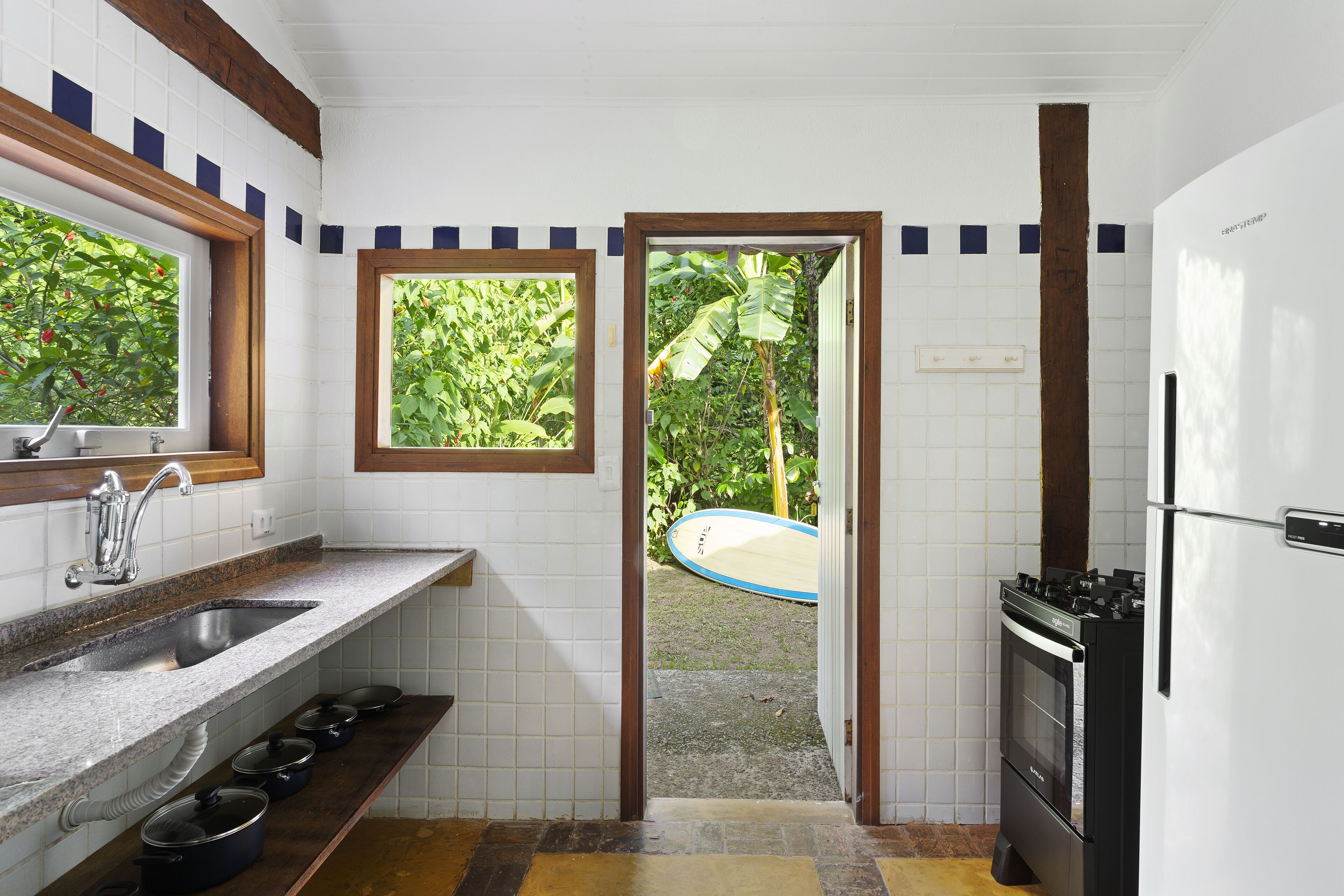 A compact kitchen with a built-in oven, a sink, and a window overlooking a garden.