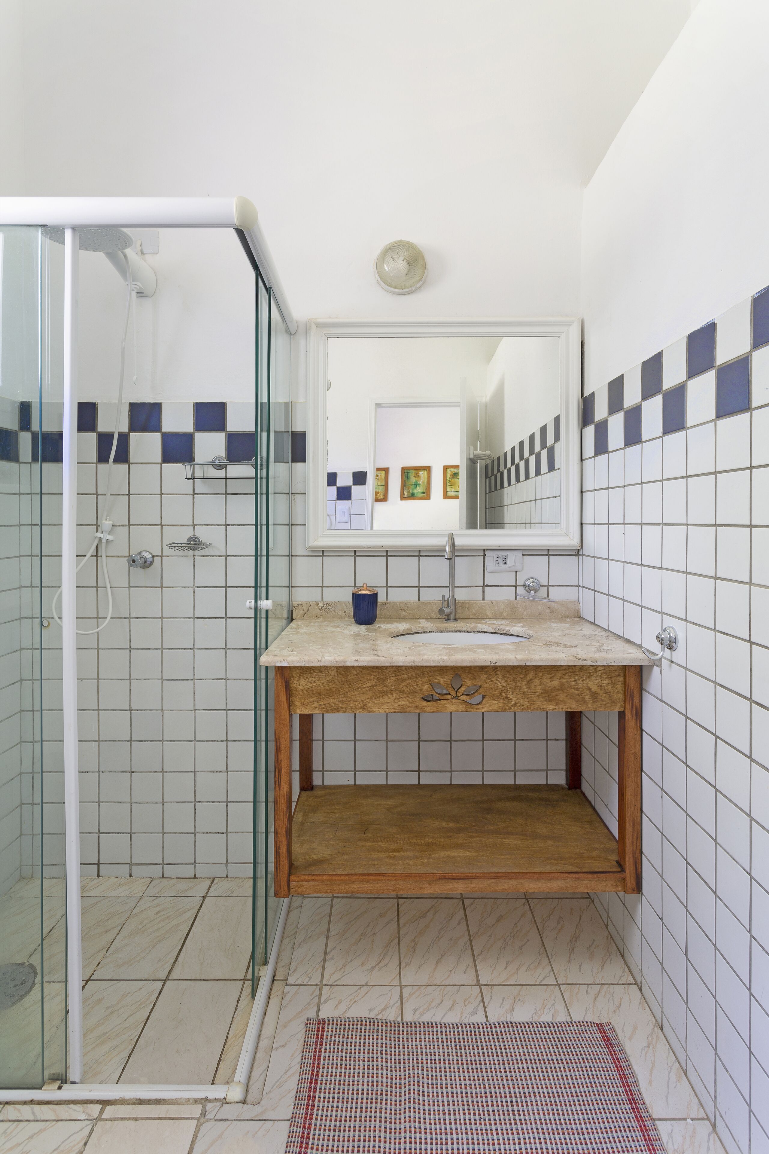 A bathroom with a glass shower enclosure, a wooden vanity with a sink, and tiled walls.