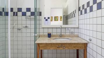 A bathroom with a glass shower enclosure, a wooden vanity with a sink, and tiled walls.
