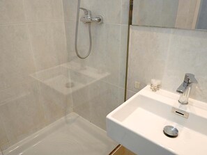 Ein Badezimmer mit Dusche, Waschbecken und Spiegel.