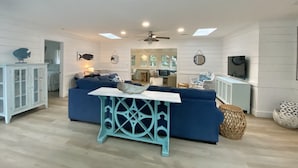 Ein Wohnzimmer mit einem blauen Sofa, einer weißen Kommode und einem Deckenventilator.