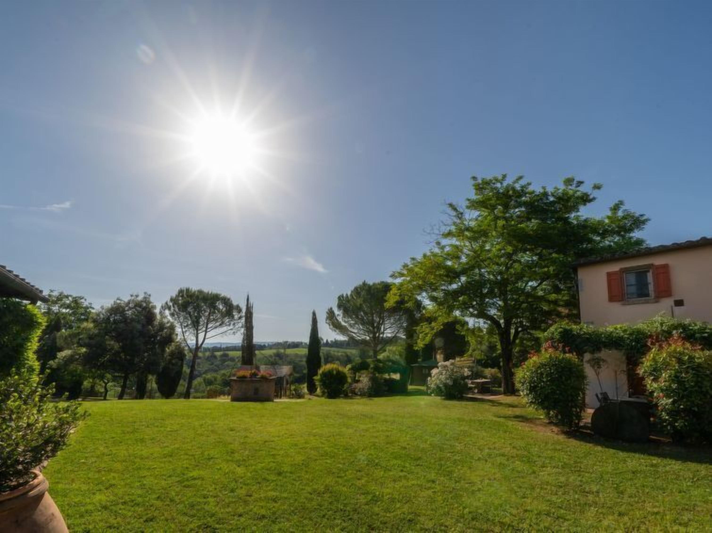 Ein sonniger Tag in einem gepflegten Garten mit einem Haus, Bäumen und blauem Himmel.