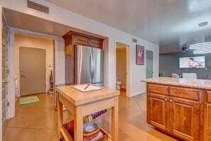 A modern kitchen with wooden cabinets, a stainless steel refrigerator, and a granite countertop.