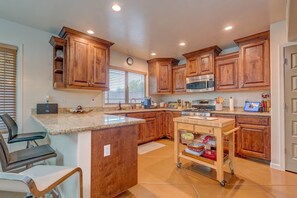 A kitchen with wooden cabinets, granite countertops, a stainless steel oven, and a small island with a sink.