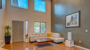 A spacious living room with a large sectional sofa, a coffee table, and a potted plant.