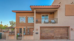 A two-story house with a garage, a balcony with outdoor furniture, and a covered patio area.