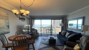 Een ruime woonkamer met een eetgedeelte, een balkon met uitzicht op zee, en een kroonluchter.