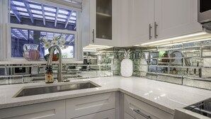 Eine moderne Küche mit weißen Schränken, einer Edelstahlspüle und einer Spritzschutzwand mit Glasfliesen.
