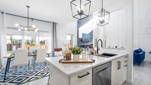 Een moderne keuken met witte kastjes, een centraal eiland en hanglampen.