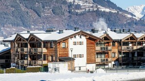 Una hilera de edificios tipo chalet de madera con balcones, con montañas nevadas al fondo.