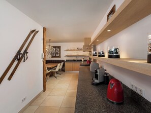 Una cocina moderna con estantes de madera, un comedor con banco y una cafetera.