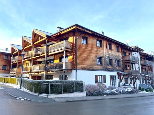 Un edificio de madera de varios pisos con balcones, un paisaje nevado y cielo despejado.
