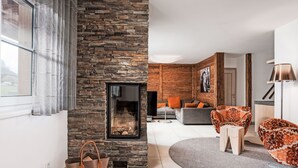 Una sala de estar moderna con una chimenea de piedra, un sofá, una mesa de centro y un sillón estampado.