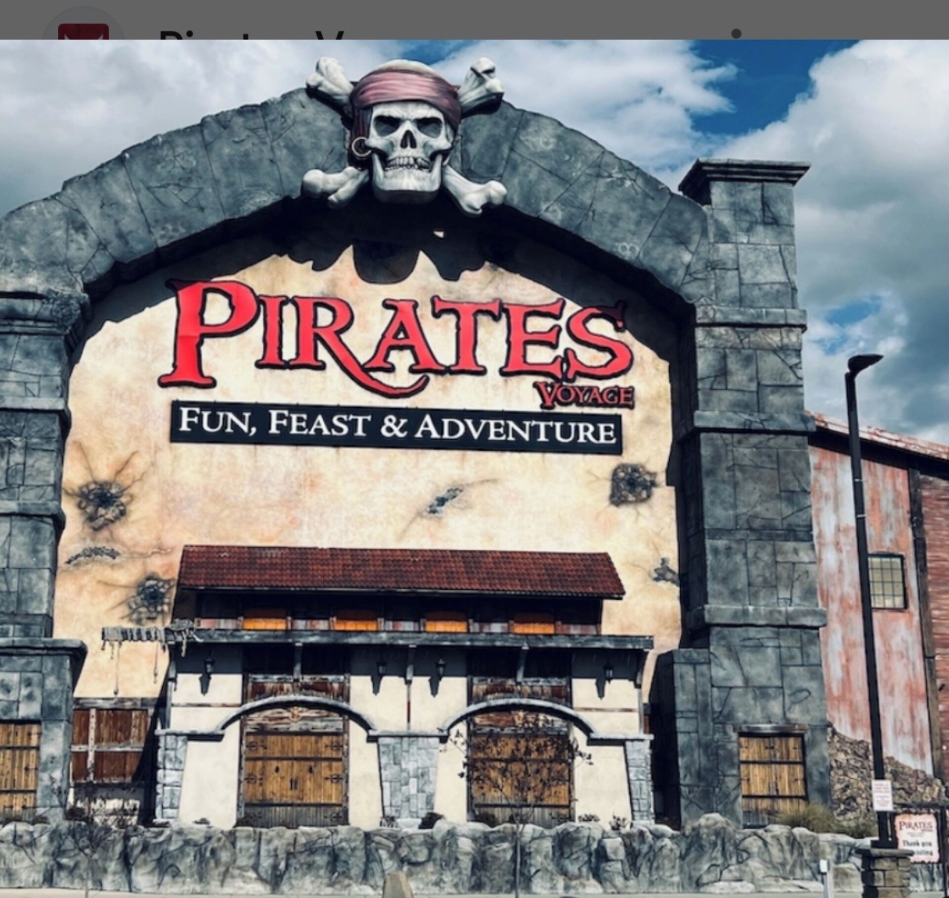 Fachada de edificio con un gran letrero que dice 'Pirates Voyage' y las palabras 'Diversión, Banquete y Aventura' debajo.
