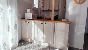 Una cocina funcional con microondas, armarios y un reloj en la pared.