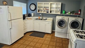 A compact kitchen with a refrigerator, sink, stove, and built-in washer and dryer. - Cozy Retreat with a Fenced Yard (Huber Heights)